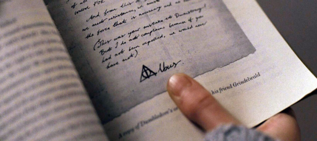 Hermione's finger pointing at the Deathly Hallows symbol in Dumbledore's letter to Grindelwald in Rita Skeeter's book.